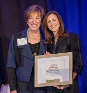 Two women smiling, one is receiving an award