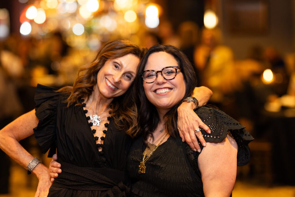 Two women arm in arm smiling
