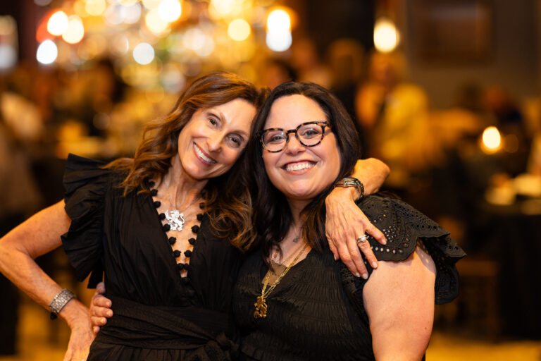 Two women arm in arm smiling