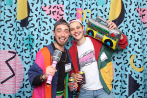 two young men in 90s clothes with a microphone and boom box.