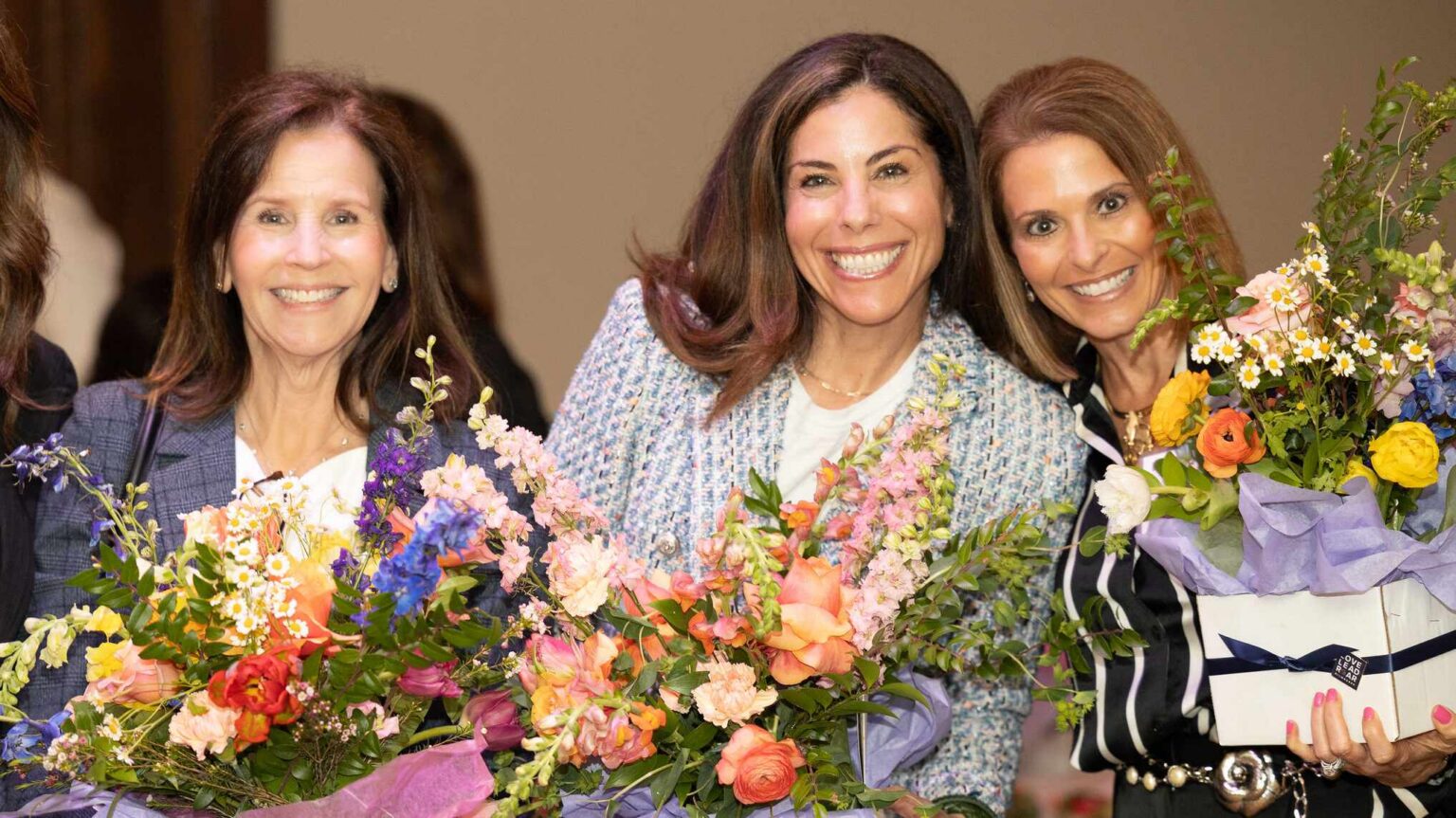 Three professional women holding bouquets of flowers