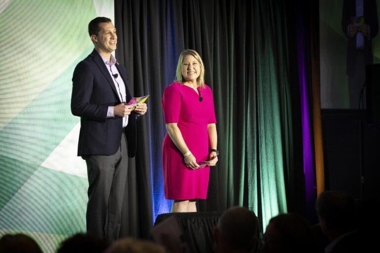 A man and woman standing on stage at an event