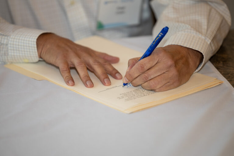 a person signing a piece of paper