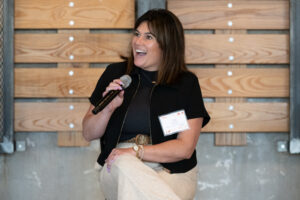 Person holding a microphone and speaking at an event.