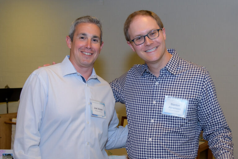 Two men in button downed shirts smiling