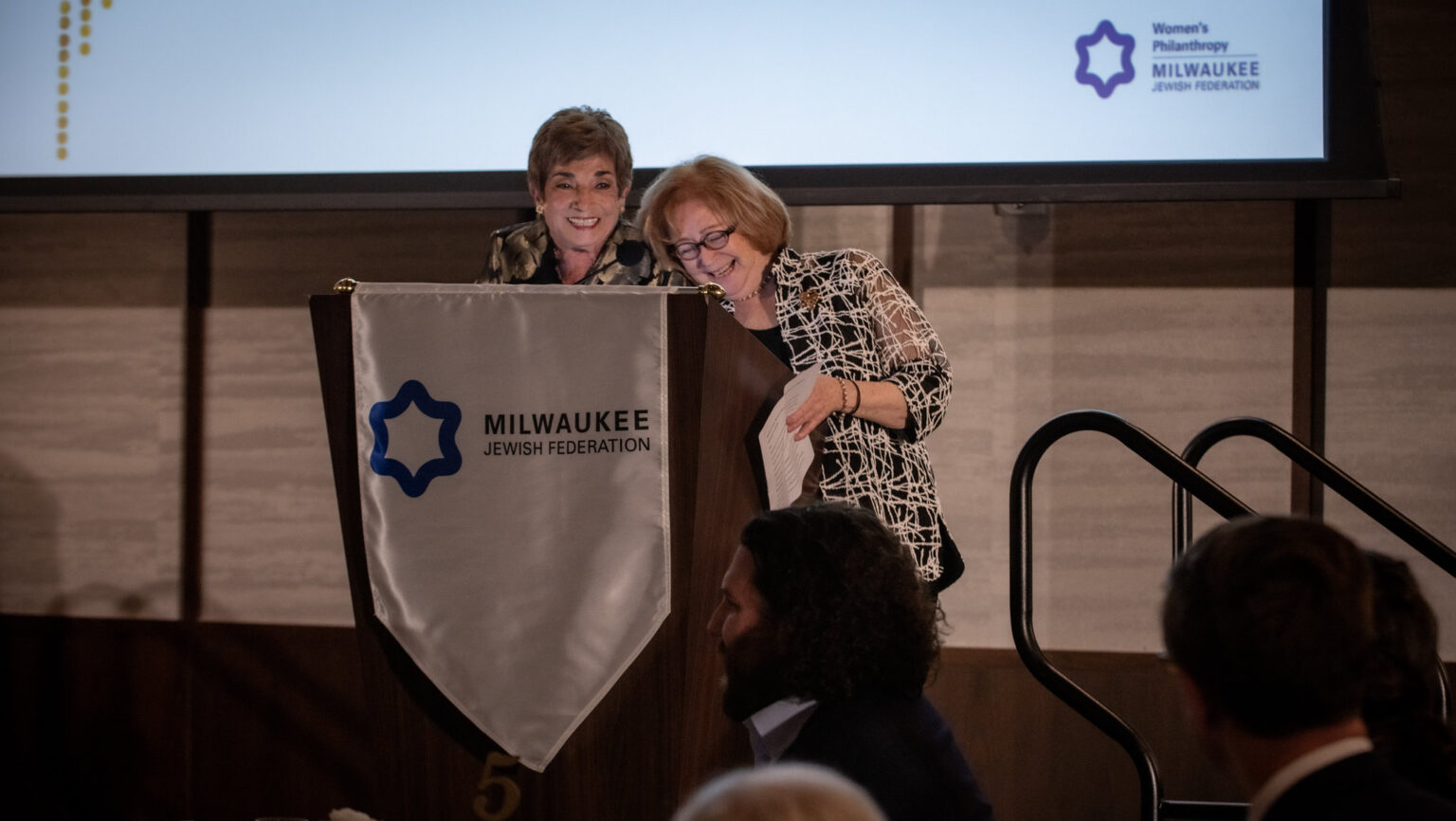 Two women laughing and smiling at a podium
