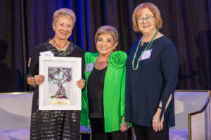 three women, one holding an award