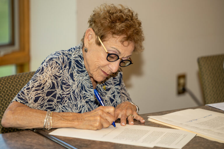 woman sitting at a table signing a paper