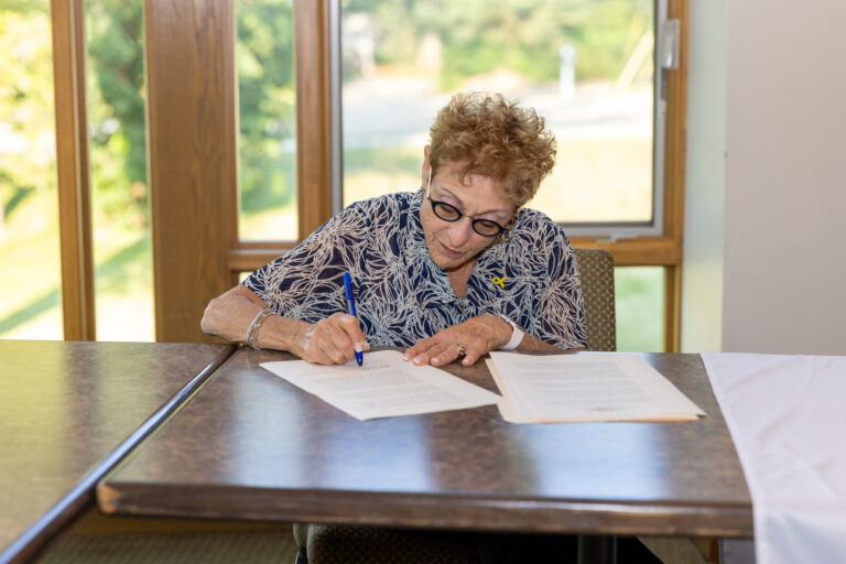 woman sitting at table signing a paper