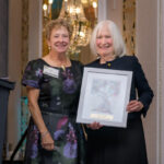 two women, one holding an award