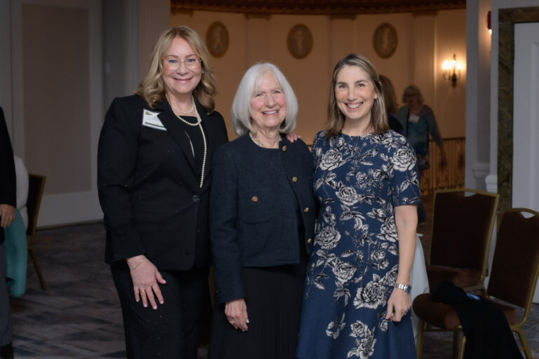 Three professional looking women smiling at an event