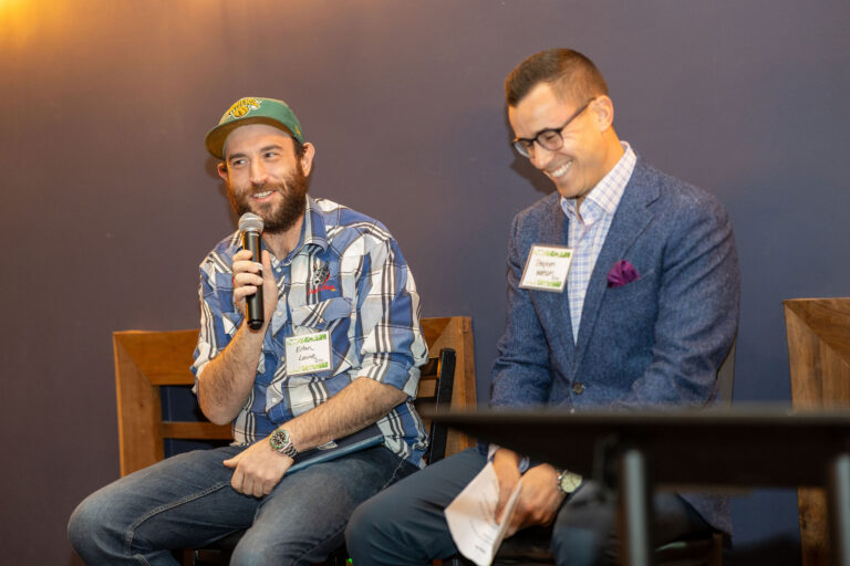 Two men smiling, one holding a microphone