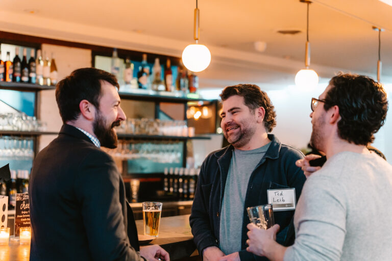 Three men laughing at a bar