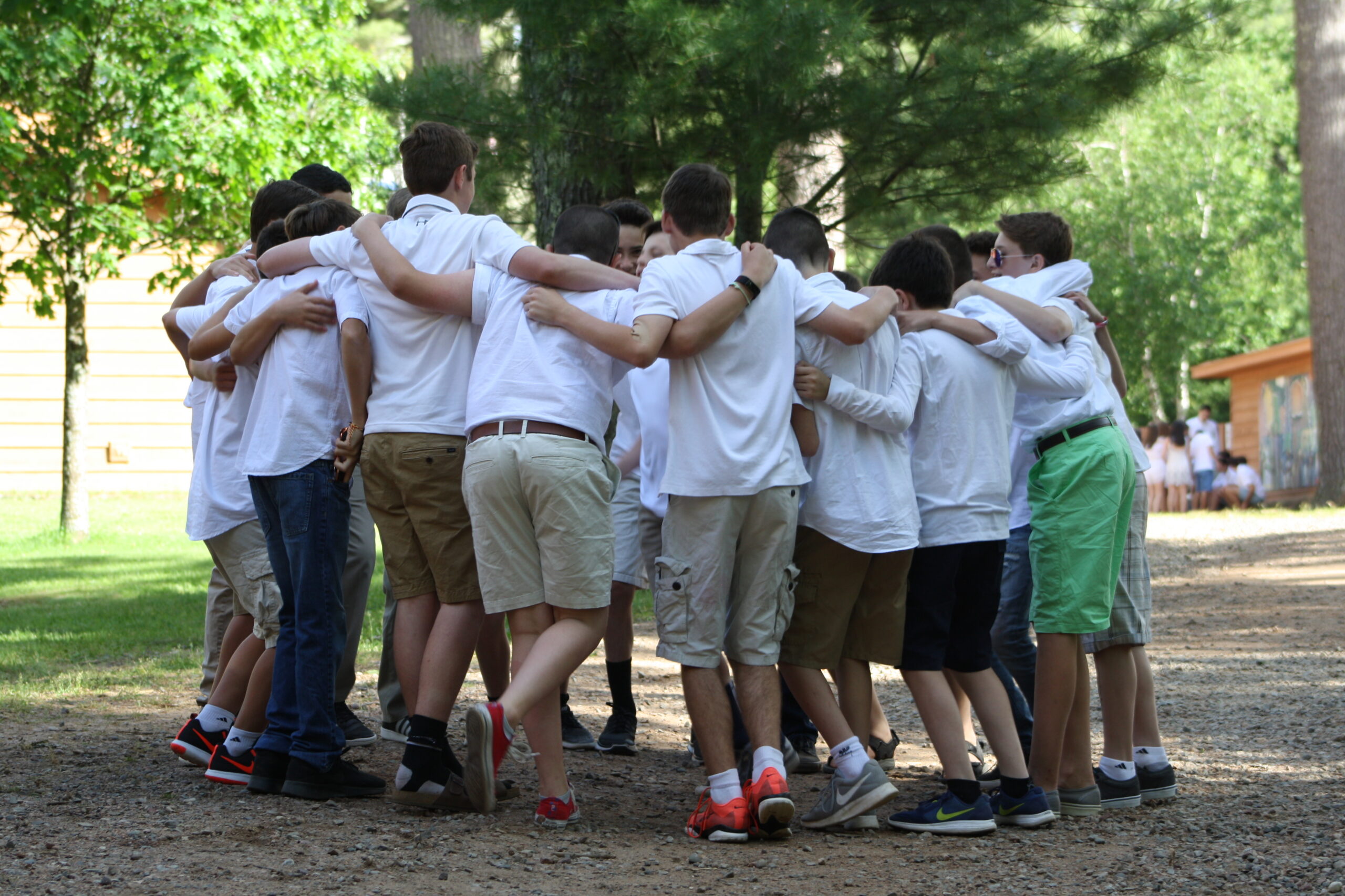 A group of teenage boys huddling together at summer camp.
