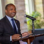 A man in a suit smiling at a podium