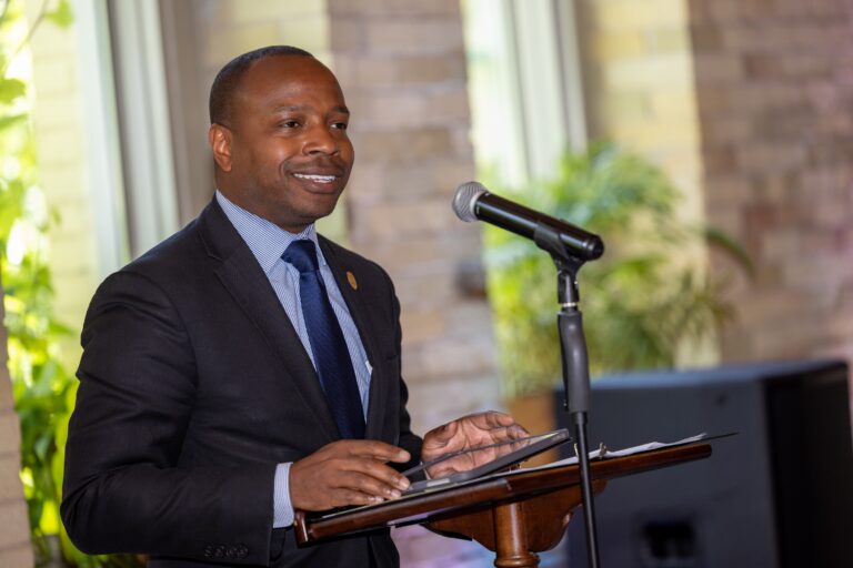 A man in a suit smiling at a podium