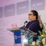 Person on speaking on stage at a meeting.