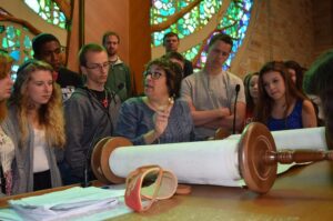 A women with a Torah scroll surrounded by a group of kids