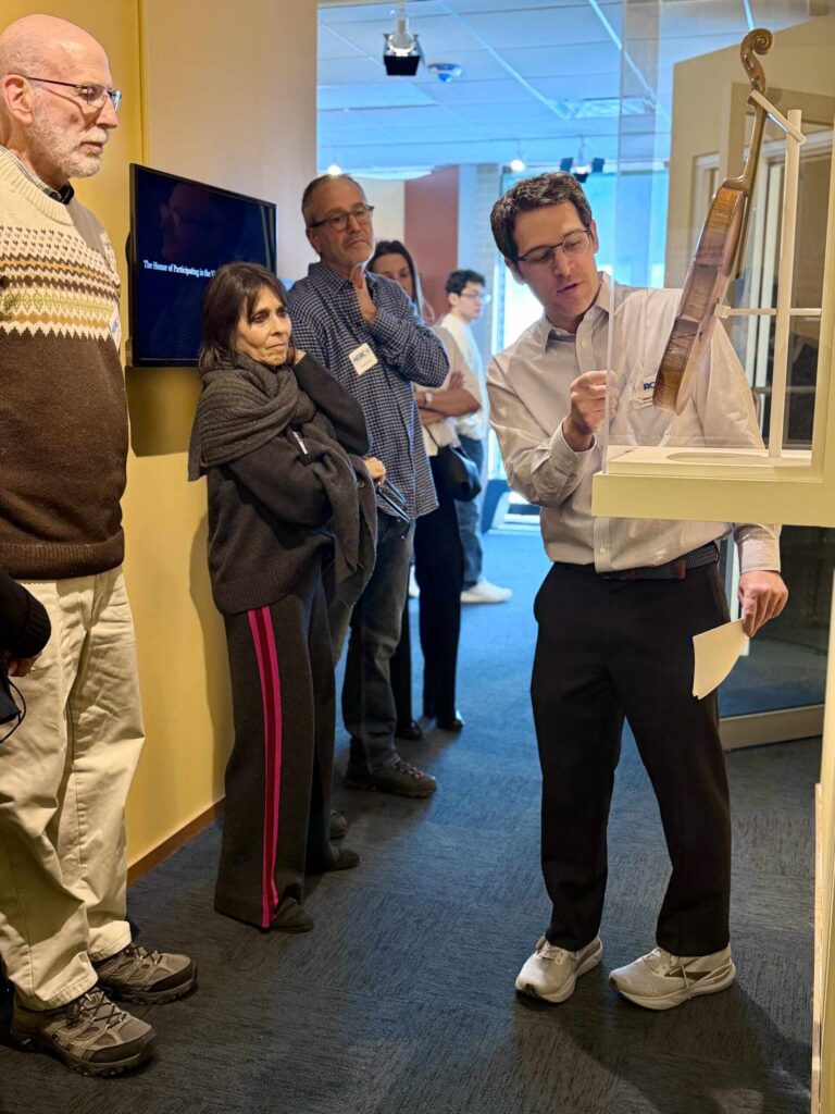 a man showing a violin as part of museum exhibit