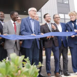 Group of people at a ribbon cutting smiling