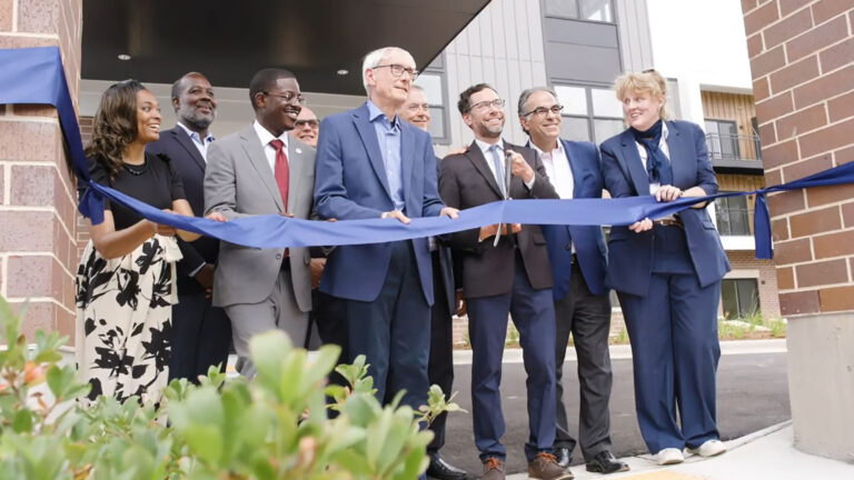 Group of people at a ribbon cutting smiling