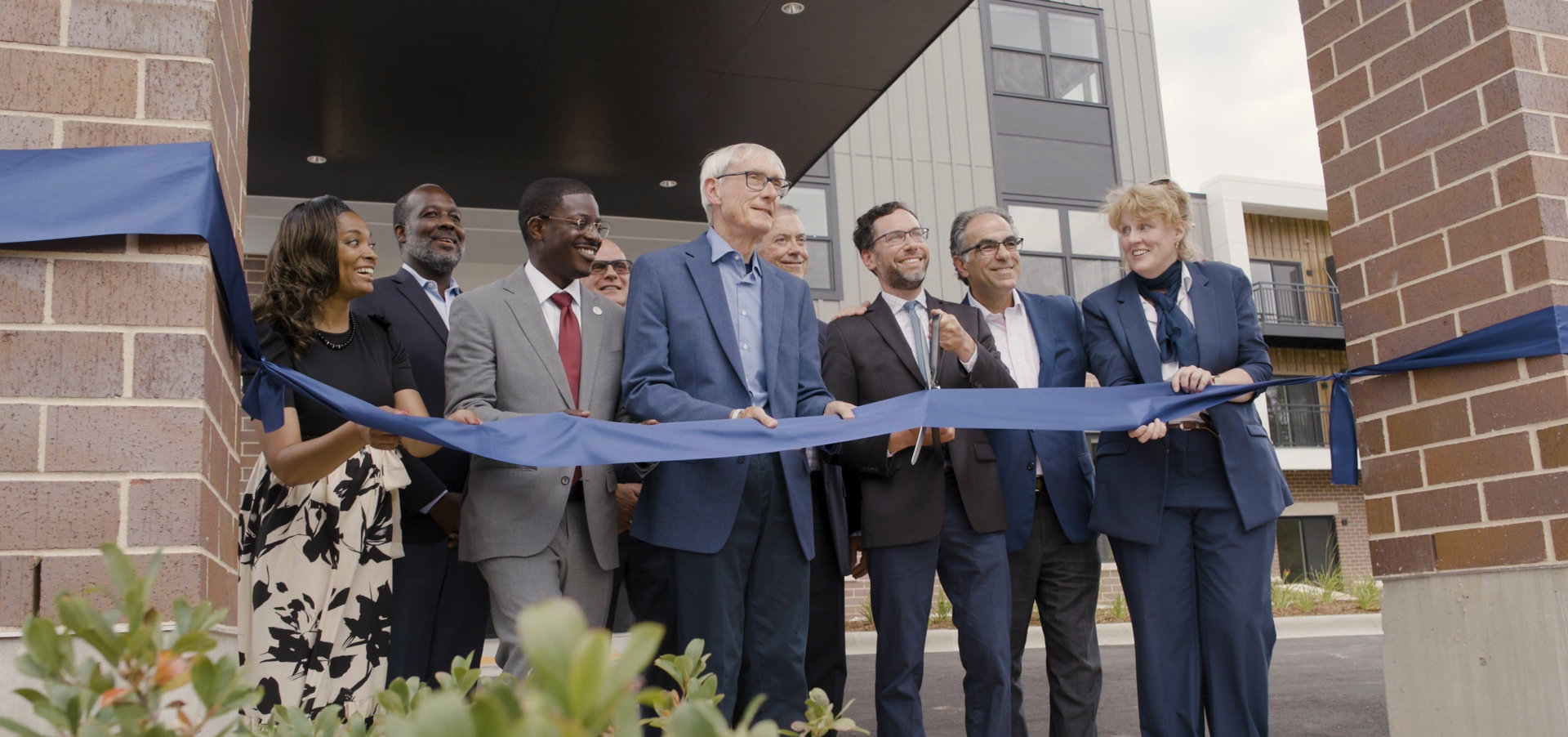 Group of people at a ribbon cutting smiling