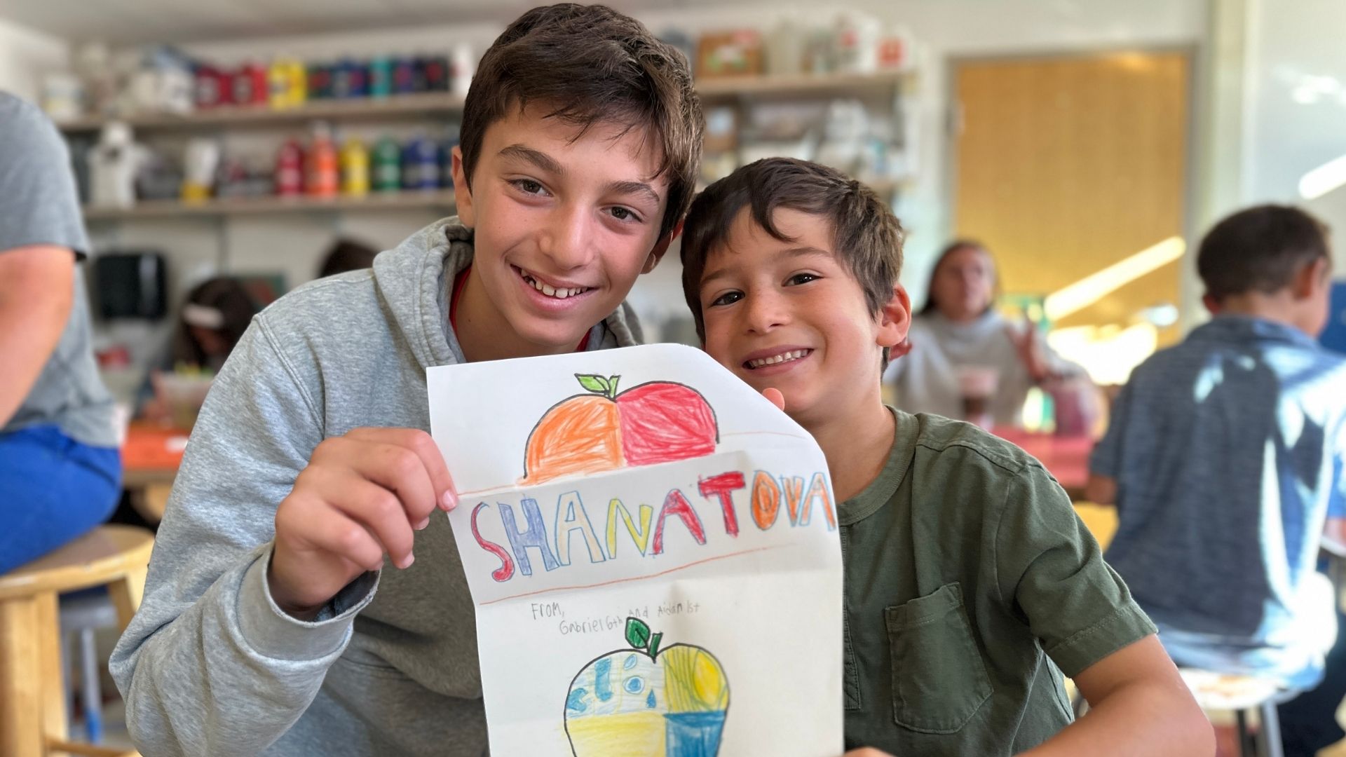 two kids showing their school artwork
