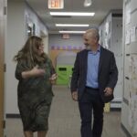 woman and man walking and talking in a hallway