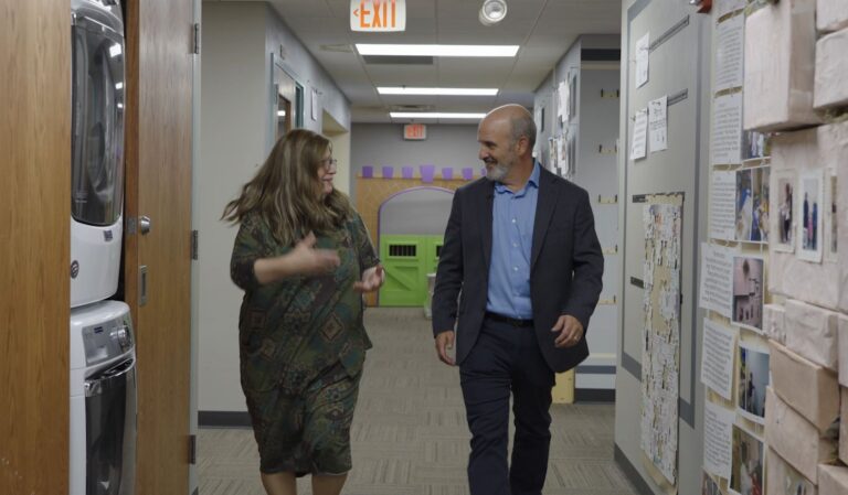 woman and man walking and talking in a hallway